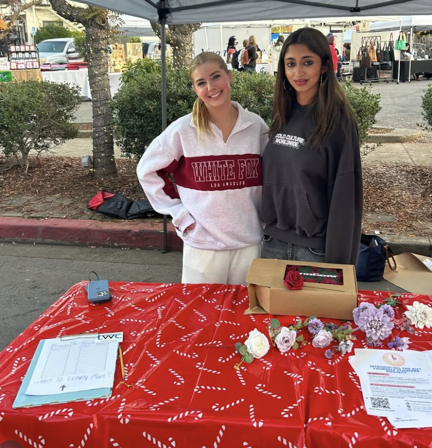 “Aanya Mukherjee and a Together We Can volunteer hosting a Buy Yourself Flowers Project booth